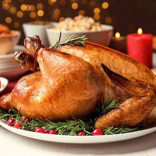A roasted turkey garnished with rosemary and cranberries is surrounded by various side dishes on a festive dining table.