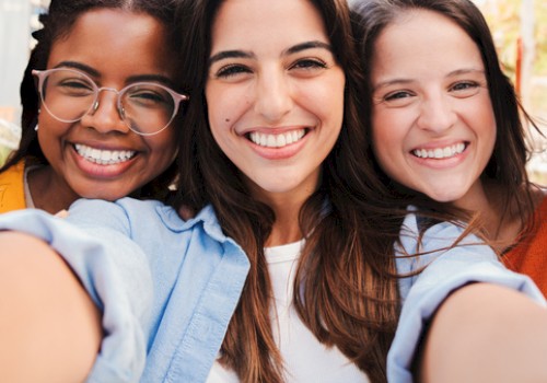 Three friends smiling for a selfie, happy and close, capturing a sunny day and good vibes.
