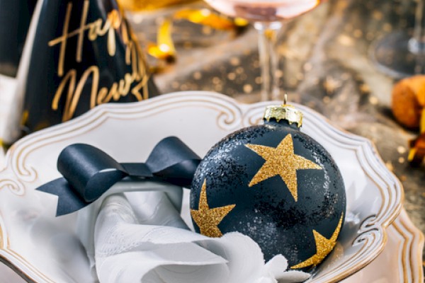 A festive table setting with a blue starry ornament, white napkin, and elegant china, a toast-worthy celebration vibe for New Year’s.