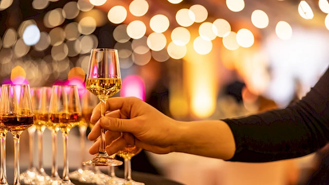 A person is pouring or preparing to serve champagne or sparkling wine at a celebration or elegant event with glowing background lights.