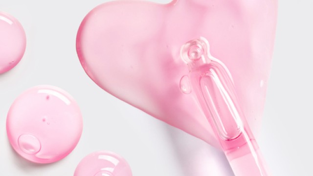 Two pink heart-shaped soaps or gels with a clear pink dropper, glossy and soft, on a light background, playful and dreamy.