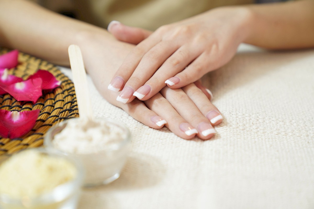 The image shows a person receiving a relaxing massage, with bowls of massage cream or lotion and rose petals nearby for ambiance.