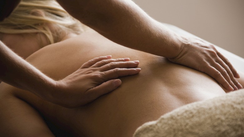 A person is receiving a massage on their back in a relaxing setting.