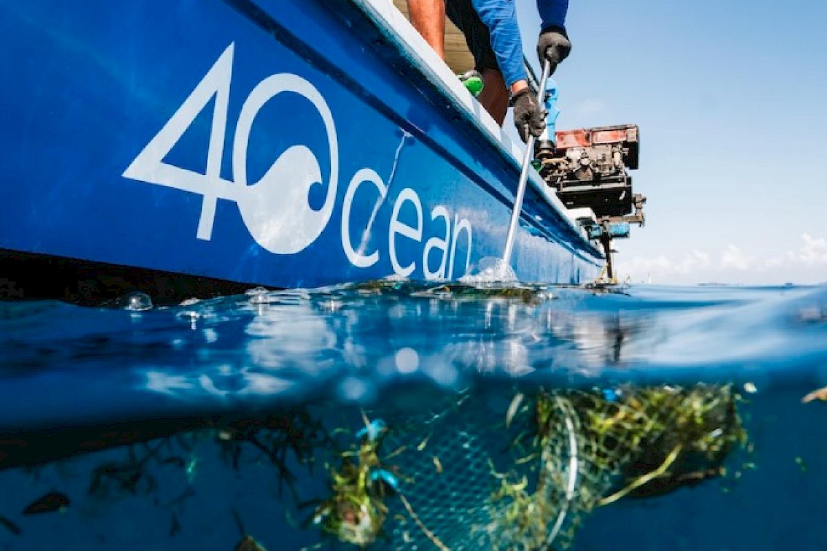 Scientists are collecting marine debris, including a plastic object, from the ocean surface near a boat labeled 