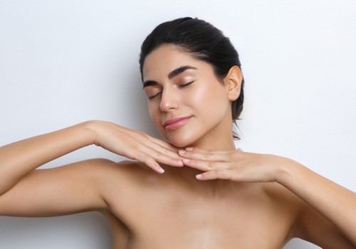 A woman with clear skin and closed eyes gently touches her face and neck, embodying relaxation and self-care.