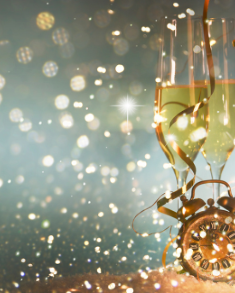 The image features two champagne glasses, a clock, and festive bokeh lights, creating a celebratory atmosphere.