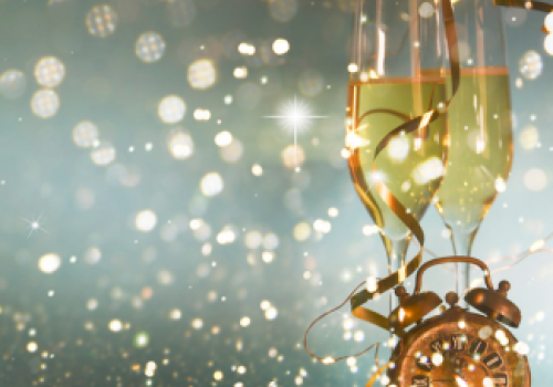 The image features two champagne glasses, a clock, and festive bokeh lights, creating a celebratory atmosphere.