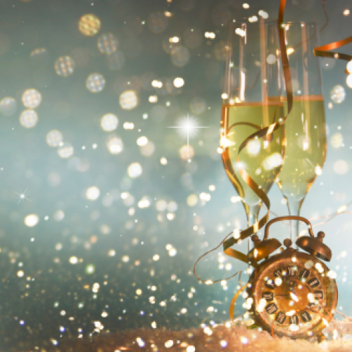 The image features two champagne glasses, a clock, and festive bokeh lights, creating a celebratory atmosphere.
