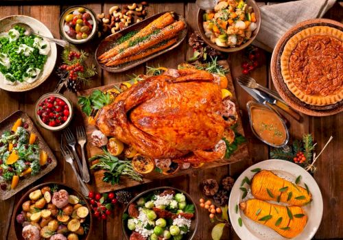 A roasted turkey with various side dishes such as mashed potatoes, stuffing, salads, corn, cranberry sauce, roasted vegetables, and pumpkin pie.