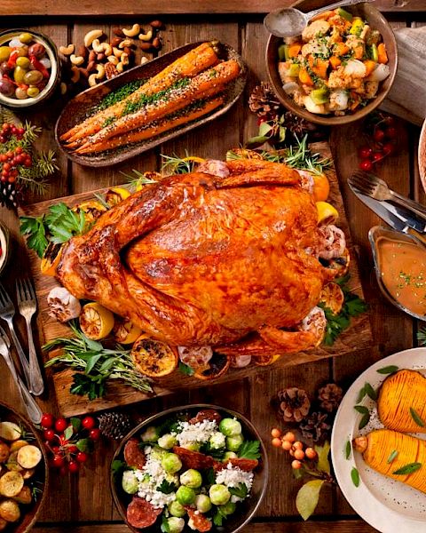 A roasted turkey with various side dishes such as mashed potatoes, stuffing, salads, corn, cranberry sauce, roasted vegetables, and pumpkin pie.