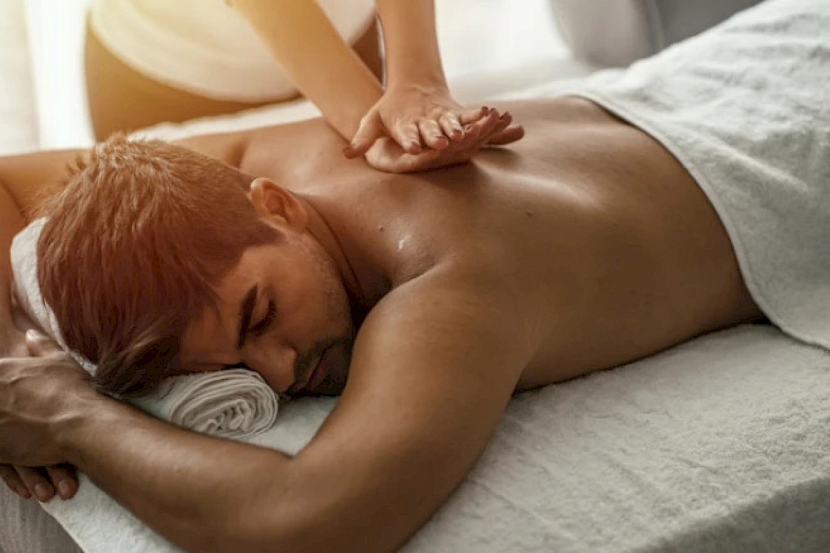 A man receives a relaxing massage on his back at a spa or massage therapy session.