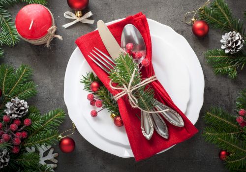 Christmas themed table setting with festive decorations and red napkin.