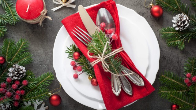 Christmas themed table setting with festive decorations and red napkin.