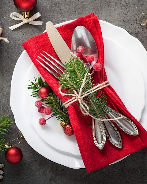 Christmas-themed table setting with festive decorations and red napkin.