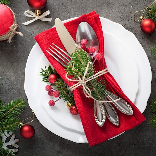 Christmas-themed table setting with festive decorations and red napkin.
