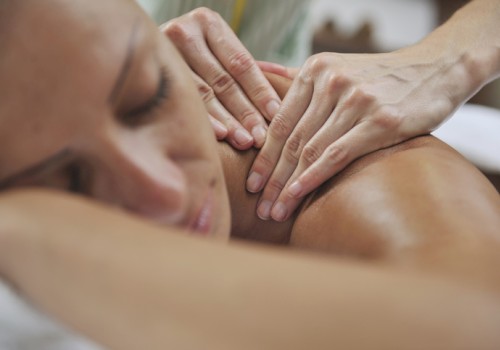 A person is receiving a back massage, lying face down, with hands applying pressure on their back for relaxation and therapy.