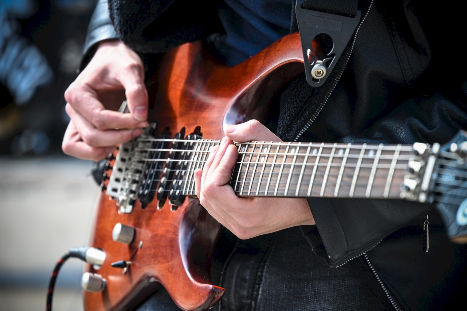 A person is playing a wooden electric guitar, focusing on their hands and the guitar's body.