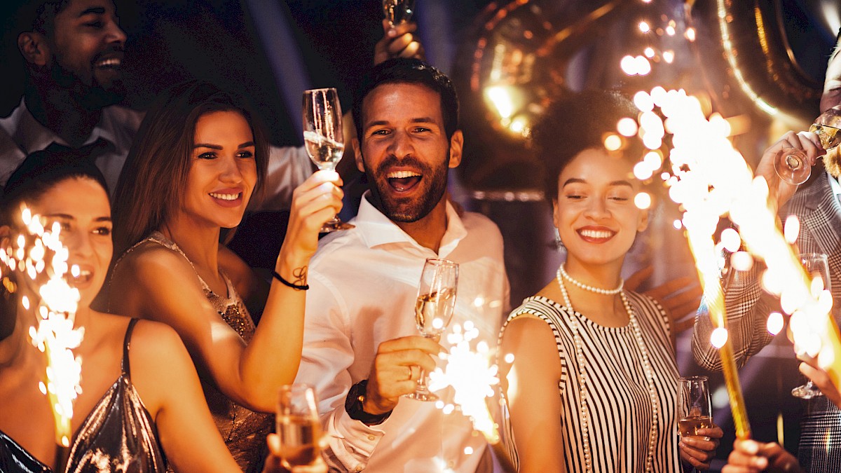 People celebrating with sparklers and glasses of champagne at a festive party.