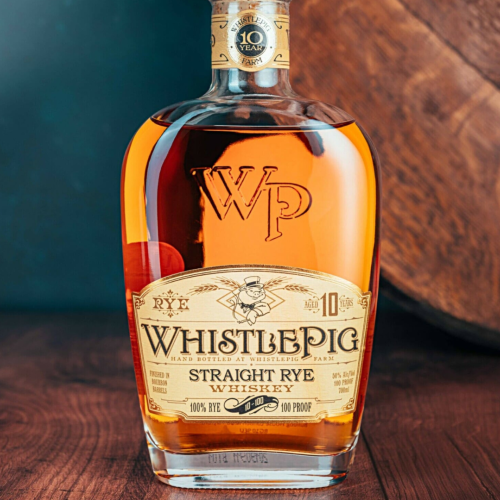 A bottle of WhistlePig 10-Year Straight Rye Whiskey is on a wooden surface, with its label prominently showing.
