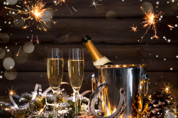 Champagne bottle in an ice bucket, two glasses, sparklers, pinecones, and festive decorations, creating a celebratory atmosphere.