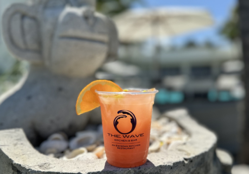 A drink with an orange slice on a stone surface next to a statue, labeled 