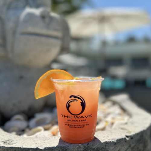 A drink with an orange slice on a stone surface next to a statue, labeled 