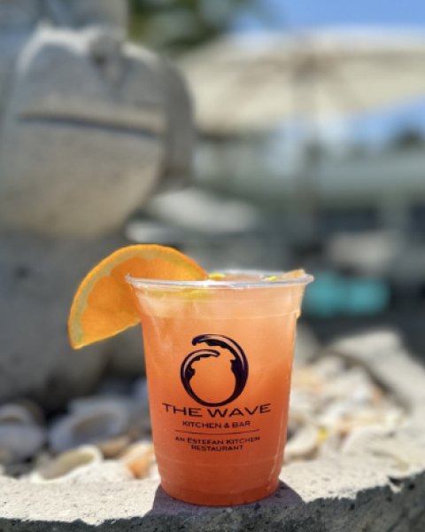 A drink with an orange slice on a stone surface next to a statue, labeled 