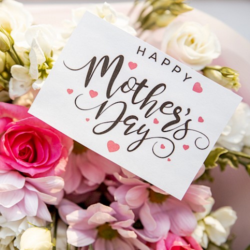 A bouquet of pink and white flowers with a “Happy Mother’s Day” card tucked among them.