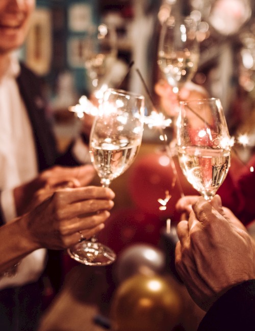 People are celebrating with sparklers and glasses of champagne, toasting in a festive gathering or party setting.