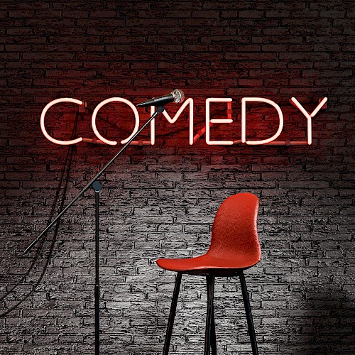 A microphone stand and a red stool in front of a brick wall with a neon sign reading 