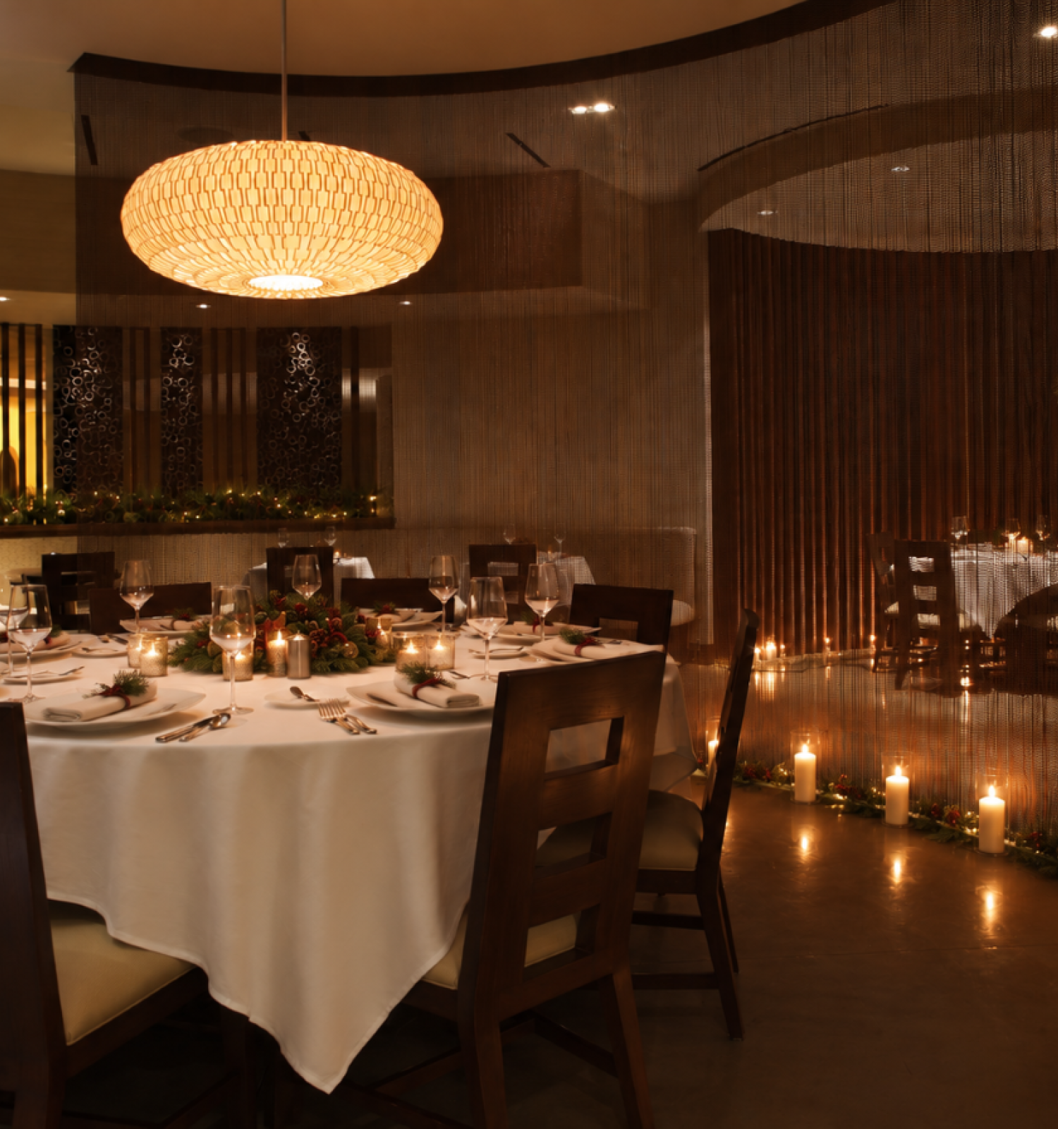 This is an elegant dining room decorated for a special occasion, featuring a round table with white linens, candles, and festive decorations.