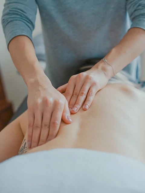 A person receiving a massage on their back from another person's hands, focusing on a soothing and relaxing experience in a calming setting.